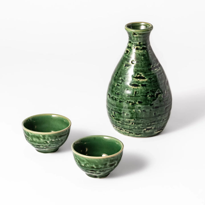 Glossy green ceramic sake flask with two matching cups featuring a textured surface and traditional Japanese craftsmanship.