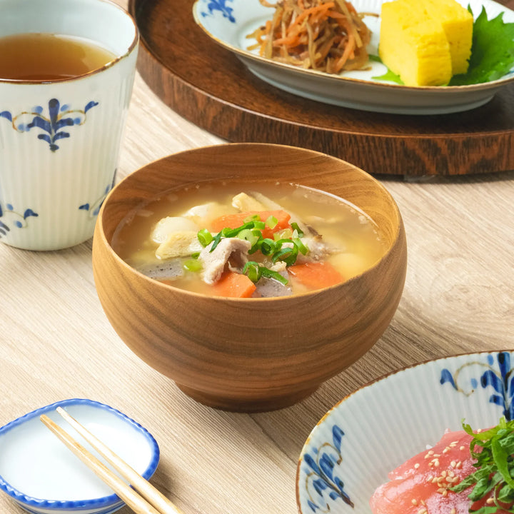 A large miso soup bowl handcrafted from cherry wood, filled with hearty vegetables and pork in a traditional Japanese meal.
