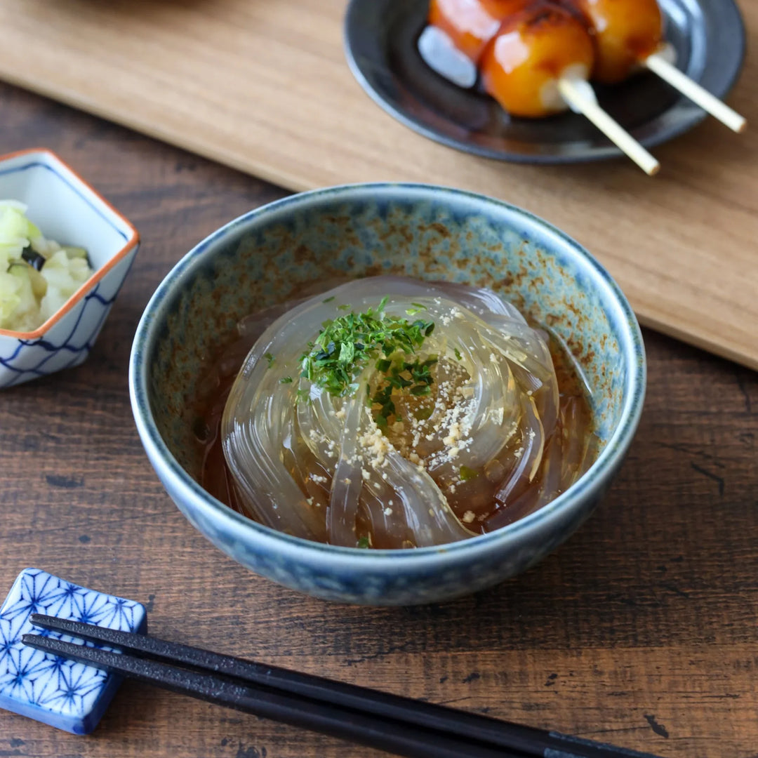 Indigo ceramic dessert bowl with a rustic glaze, beautifully presenting chilled tokoroten noodles topped with sesame and herbs for a refreshing summer dish.
