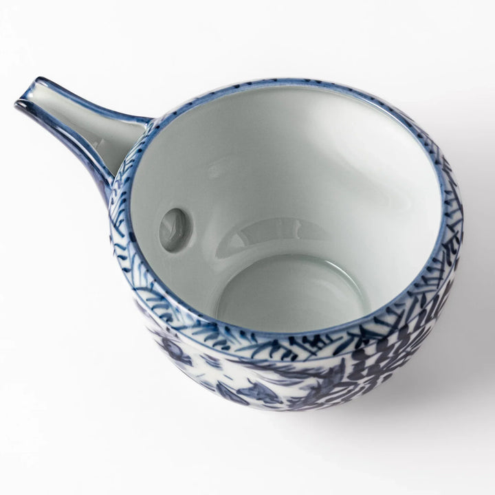 Porcelain sake pourer with spout featuring hand-painted indigo landscape and arabesque patterns in a traditional Japanese style.