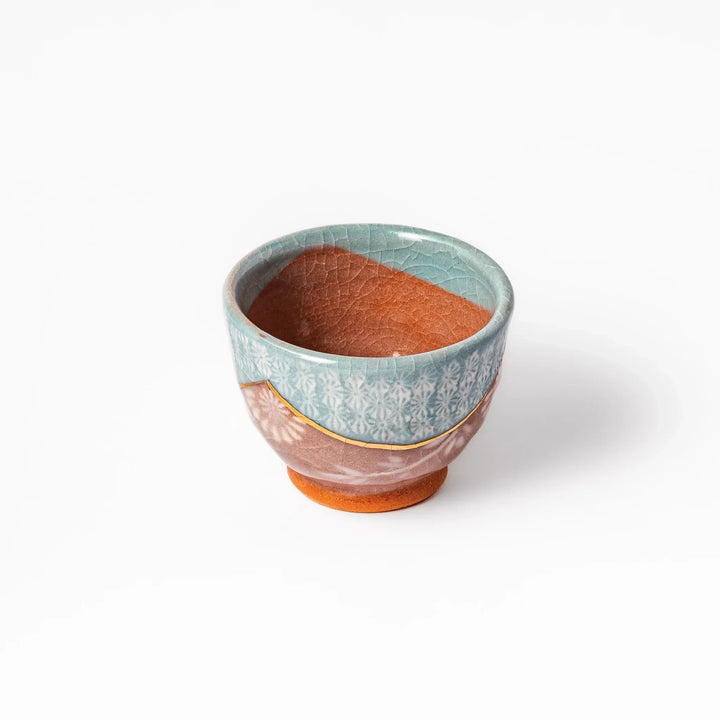 Ceramic tea cup featuring a crackled turquoise glaze with floral patterns and a contrasting earthy brown base for a handcrafted look.