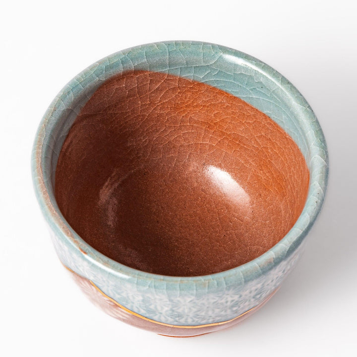 Ceramic tea cup featuring a crackled turquoise glaze with floral patterns and a contrasting earthy brown base for a handcrafted look.