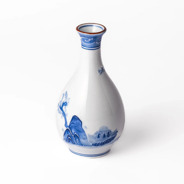Porcelain sake flask with hand-painted blue mountain and village scenery, featuring a red rim and elegant traditional silhouette.