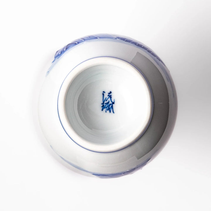 Porcelain sake flask with hand-painted blue mountain and village scenery, featuring a red rim and elegant traditional silhouette.