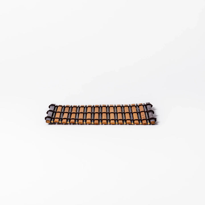Brown bamboo coaster with alternating natural and dark slats, bound with black cord, adding a rustic and refined touch to Japanese-style tableware.