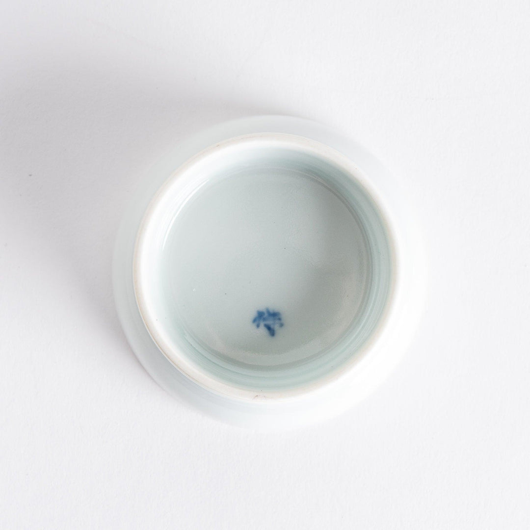 A small raised sauce dish adorned with traditional Japanese motifs, including floral and geometric patterns in red, blue, and green.