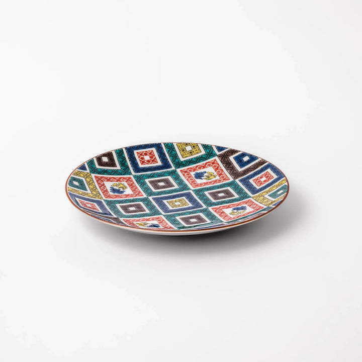 Colorful porcelain dessert plate featuring a mosaic of geometric square patterns in red, green, yellow, blue, and black with floral accents.