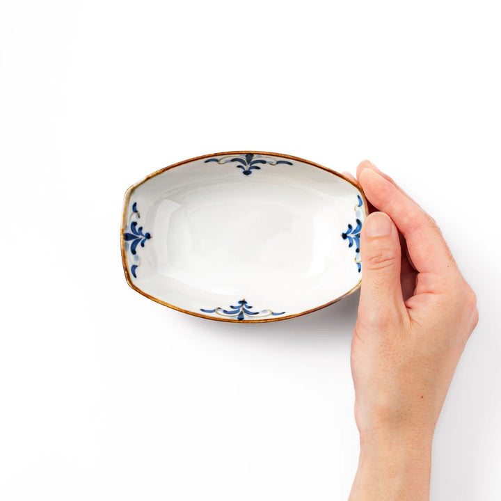 White boat-shaped bowl with blue floral patterns on the inner rim and a rustic brown edge, perfect for cereal or side dishes.