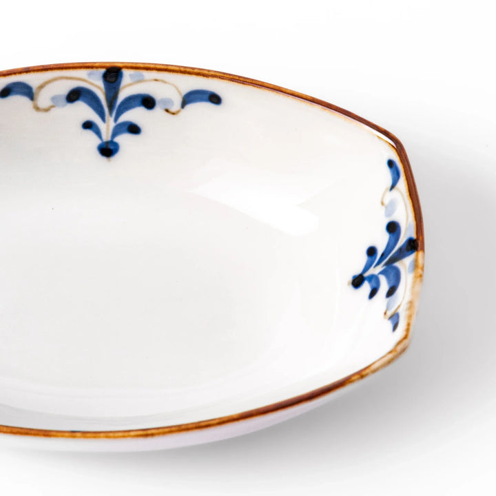 White boat-shaped bowl with blue floral patterns on the inner rim and a rustic brown edge, perfect for cereal or side dishes.