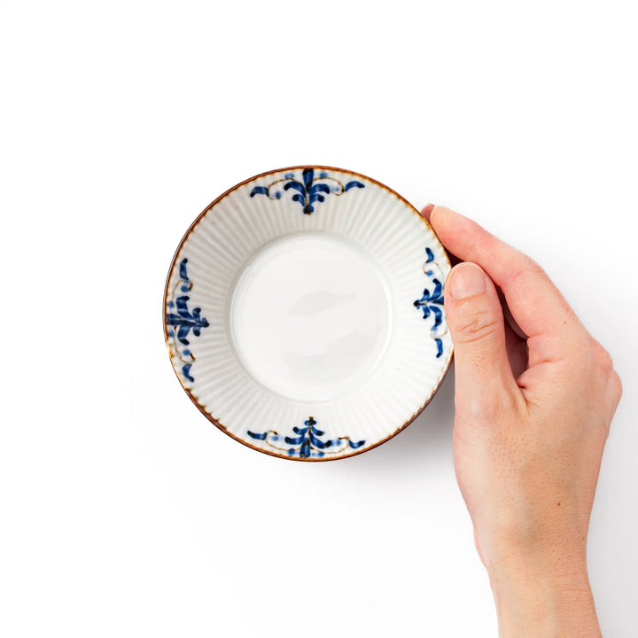 White dessert bowl with vertical ridges, blue floral accents around the rim, and a warm brown edge, perfect for sweets or fruit.