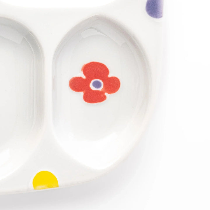 White ceramic kids plate with four divided sections, decorated with pink, yellow, red, and purple flower motifs