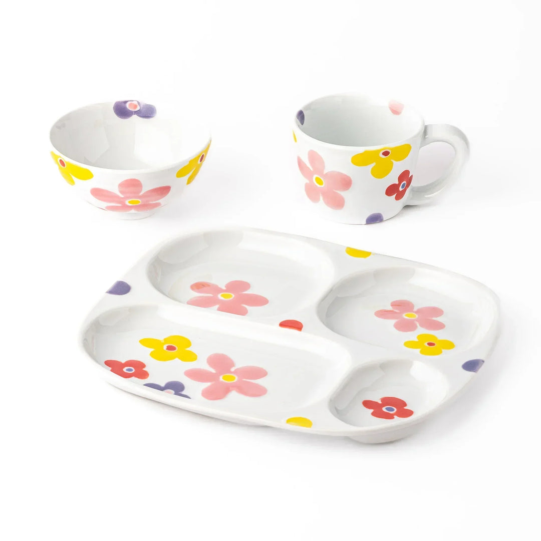 White ceramic kids plate, mug, and bowl set decorated with pink, yellow, red, and purple flowers, shown on white background