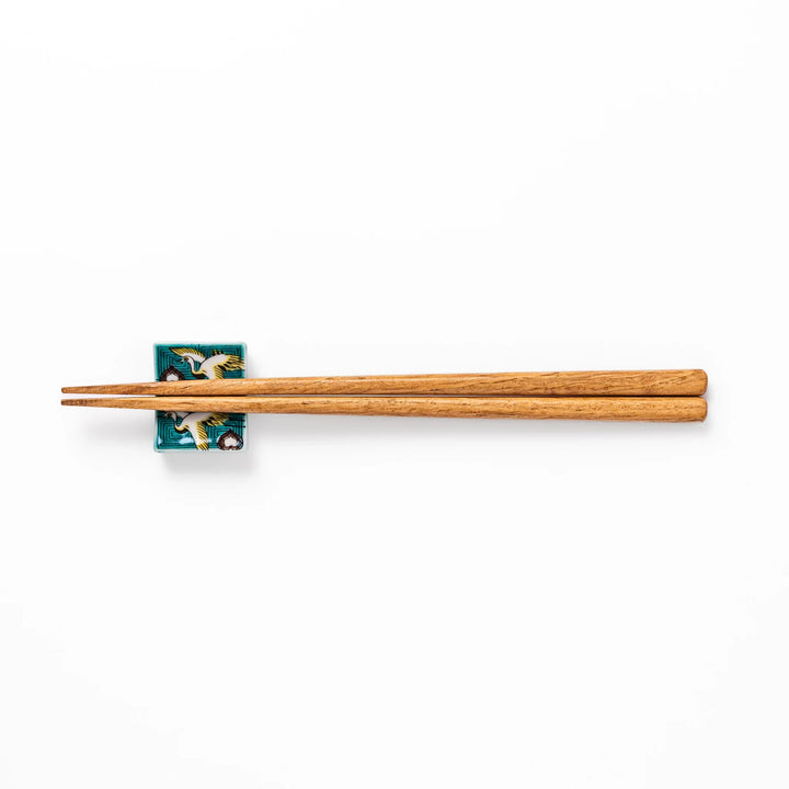 Rectangular Japanese ceramic chopstick rest featuring flying crane motif with teal geometric background and gold accents, symbolizing longevity and elegance in dining.