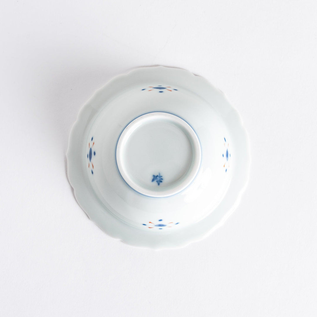 A dessert bowl with bold red and green designs around the rim, with a large blue kanji character in the center representing "fortune."