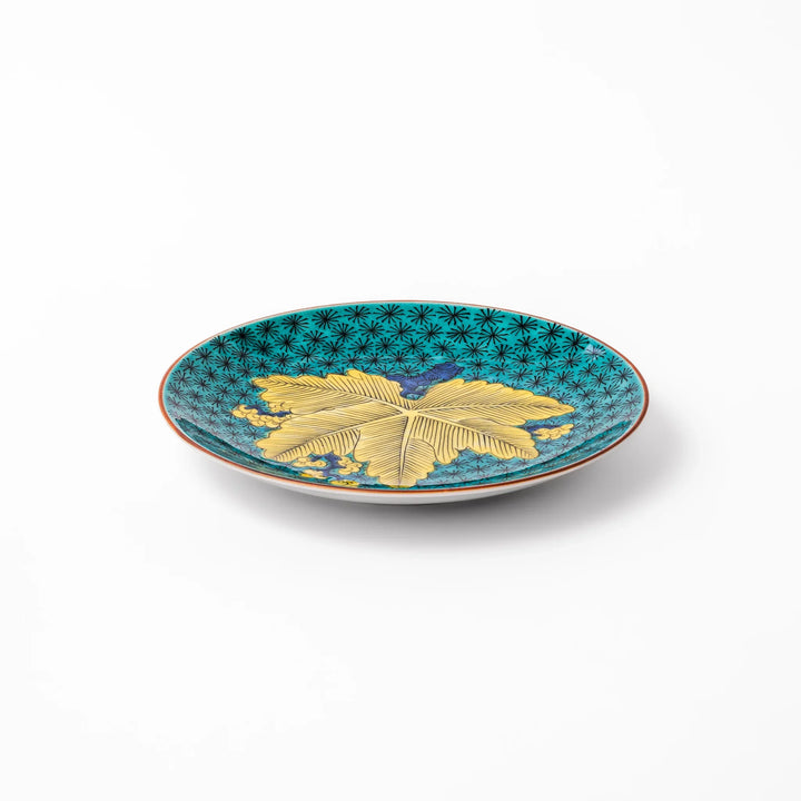 Round Kutani dessert plate with a bold golden leaf and grape motif on a turquoise background patterned with black starbursts.