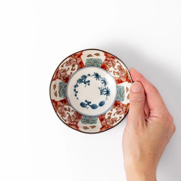 Scalloped Japanese dessert bowl with vibrant red, green, and gold patterns and a blue floral center, ideal for elegant traditional table settings.