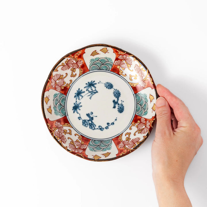 Elegant Japanese dessert plate with a scalloped edge, blue floral center, and red, gold, and green traditional patterns perfect for refined table settings.