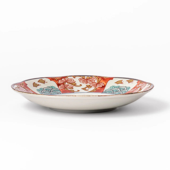 Elegant Japanese dessert plate with a scalloped edge, blue floral center, and red, gold, and green traditional patterns perfect for refined table settings.