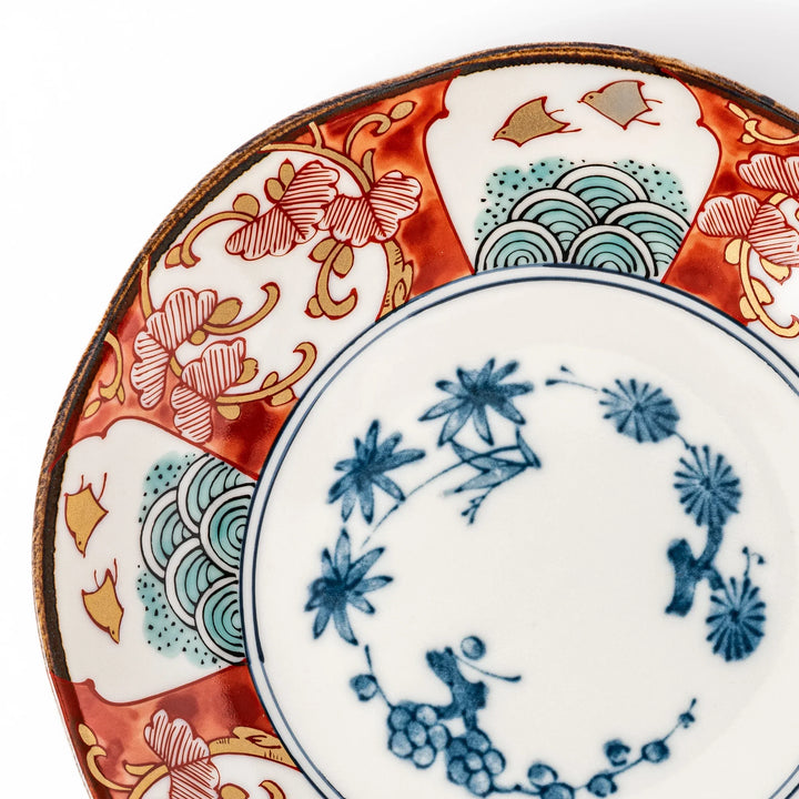 Elegant Japanese dessert plate with a scalloped edge, blue floral center, and red, gold, and green traditional patterns perfect for refined table settings.