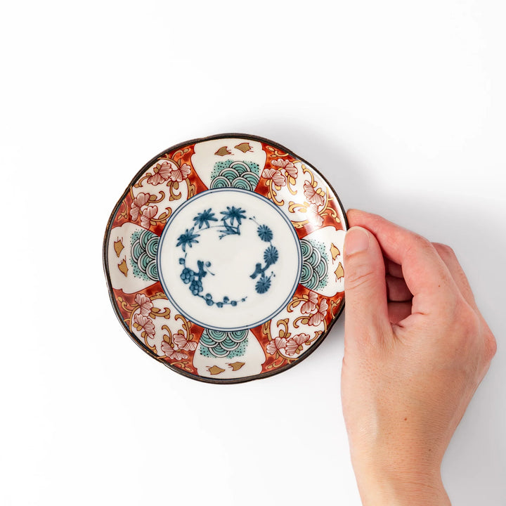 Scalloped edge sauce dish featuring red, blue, and green traditional Japanese motifs with a floral center, perfect for elegant table presentations.