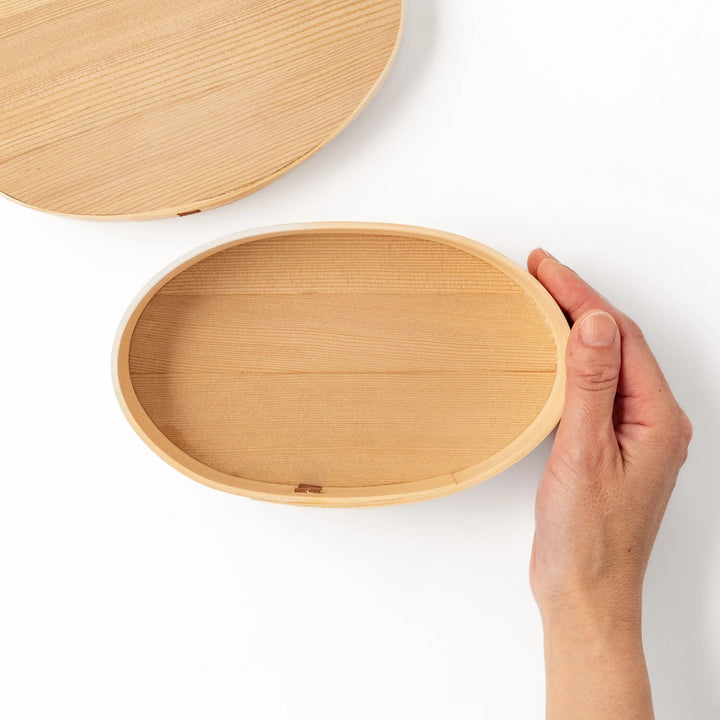 Oval bento box handcrafted from smooth hinoki wood with traditional joinery, offering a lightweight and aromatic way to carry Japanese-style meals.