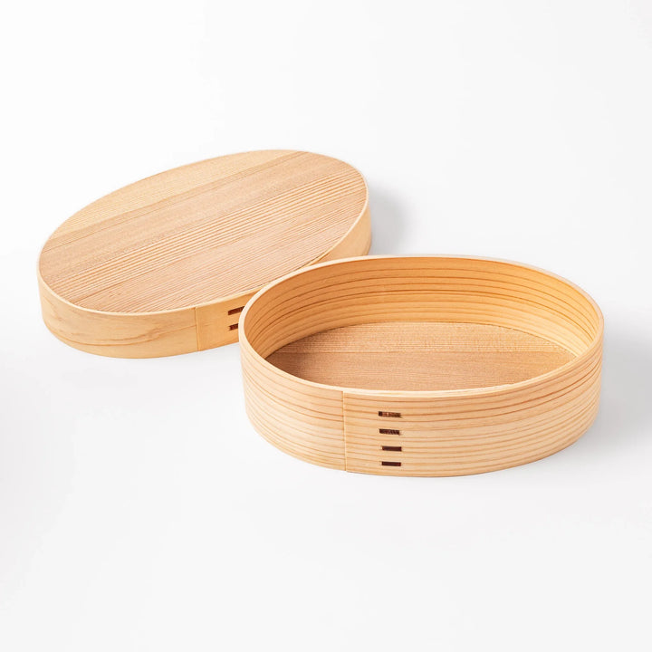 Oval bento box handcrafted from smooth hinoki wood with traditional joinery, offering a lightweight and aromatic way to carry Japanese-style meals.