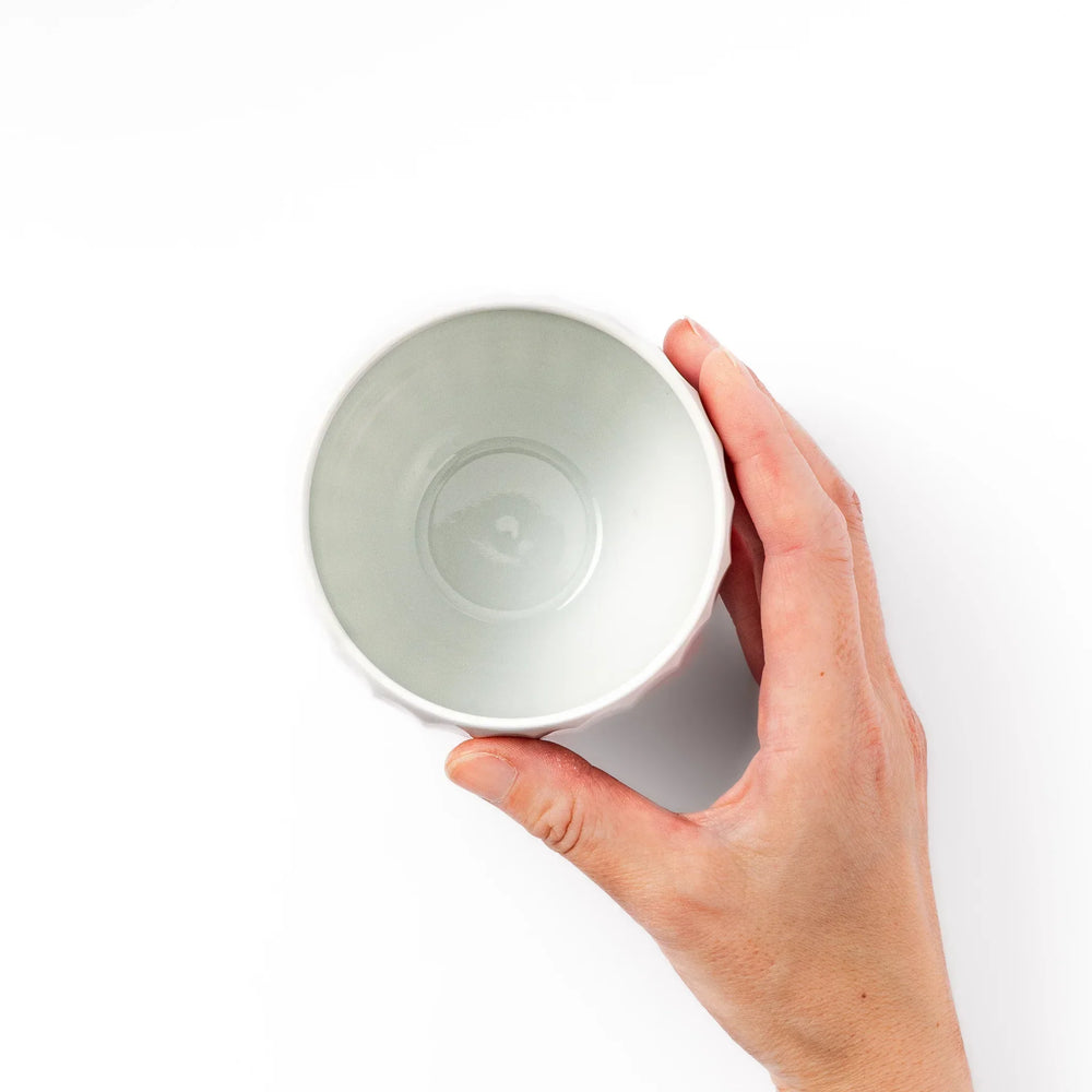 White teacup with vertical petal-like grooves and glossy finish, ideal for serving hot tea with a refined and modern aesthetic.