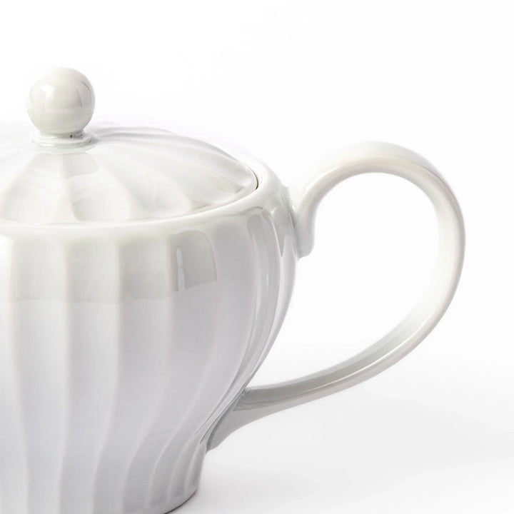White teapot with vertical petal-inspired ridges and a round lid, perfect for a refined and elegant tea presentation.