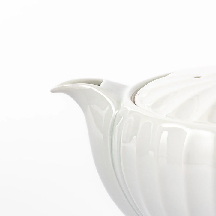 White teapot with vertical petal-inspired ridges and a round lid, perfect for a refined and elegant tea presentation.