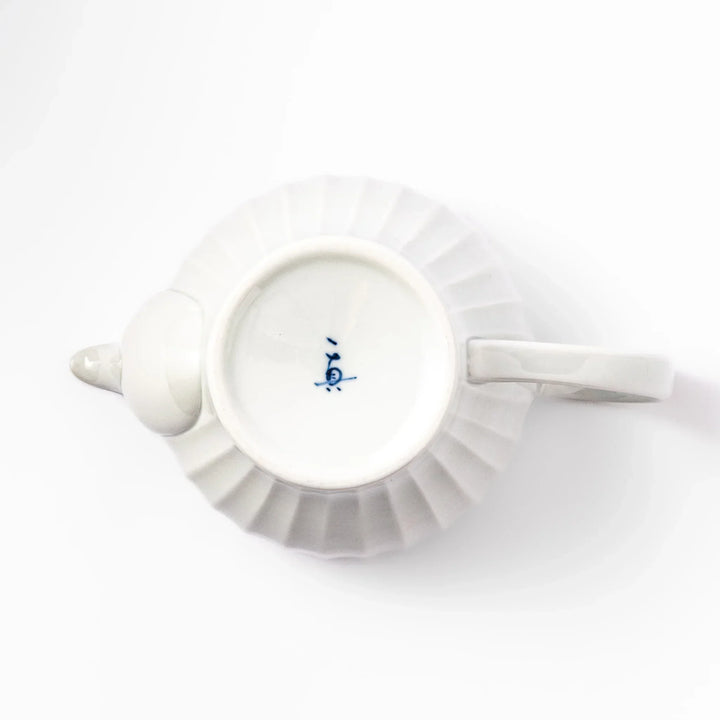 White teapot with vertical petal-inspired ridges and a round lid, perfect for a refined and elegant tea presentation.