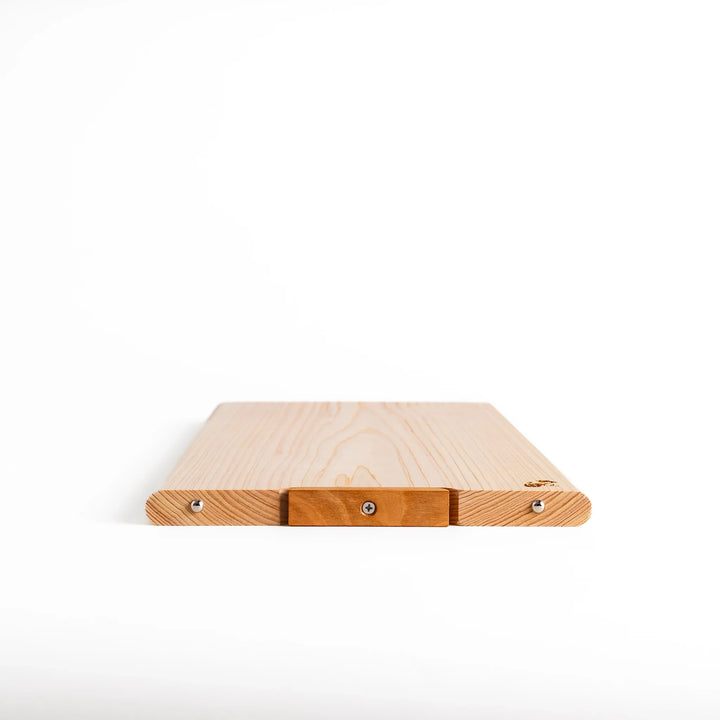 Hinoki wood cutting board with natural grain, engraved logo, and attached base for upright storage, combining beauty with everyday function.