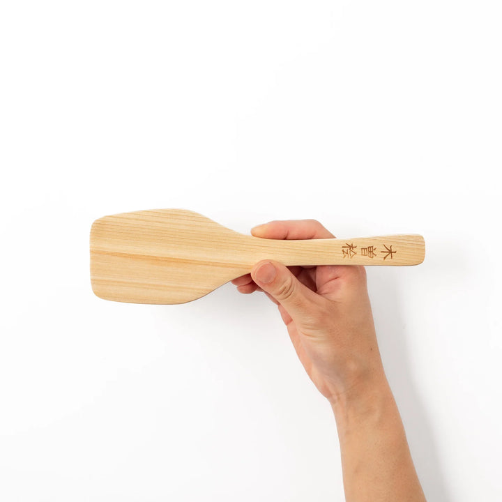 Compact hinoki wood spatula with a flat, angled edge and engraved handle, perfect for straining, flipping, and serving delicate dishes.