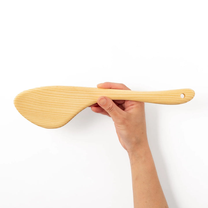 Curved spatula crafted from natural hinoki wood, featuring a wide paddle and smooth grain, perfect for stir-frying and gentle cooking tasks.