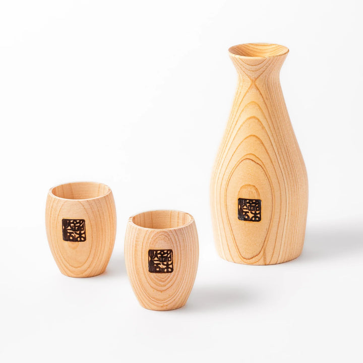 Hinoki wood sake set featuring one carafe and two cups, each adorned with an intricate burnt-in design, ideal for elevating traditional sake rituals.