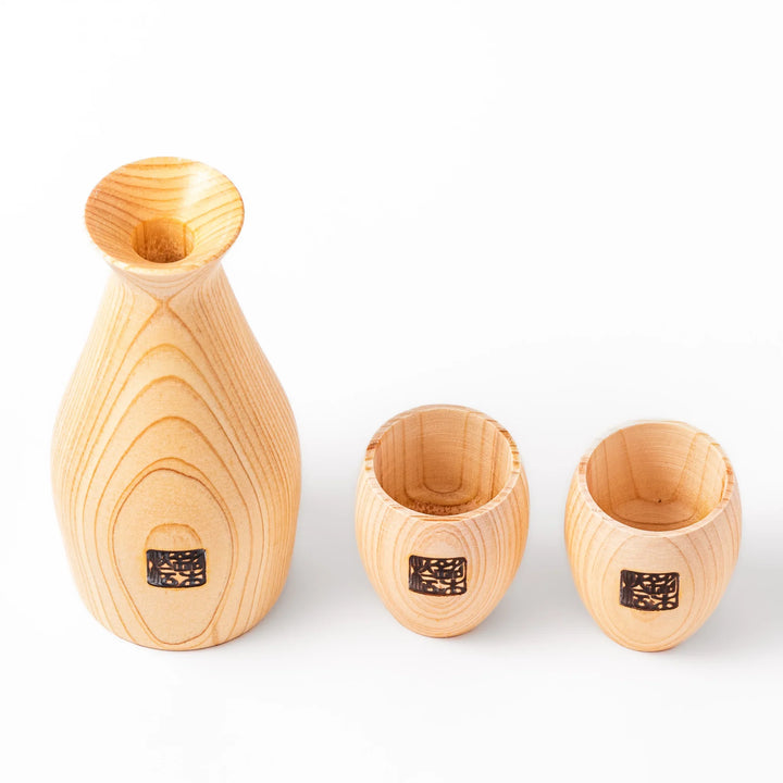 Hinoki wood sake set featuring one carafe and two cups, each adorned with an intricate burnt-in design, ideal for elevating traditional sake rituals.