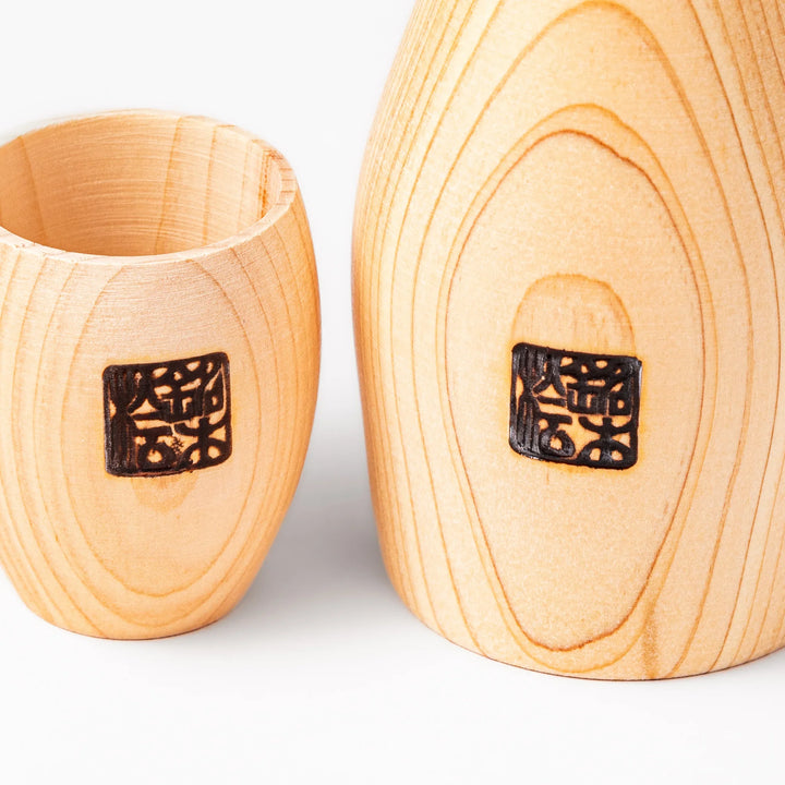 Hinoki wood sake set featuring one carafe and two cups, each adorned with an intricate burnt-in design, ideal for elevating traditional sake rituals.