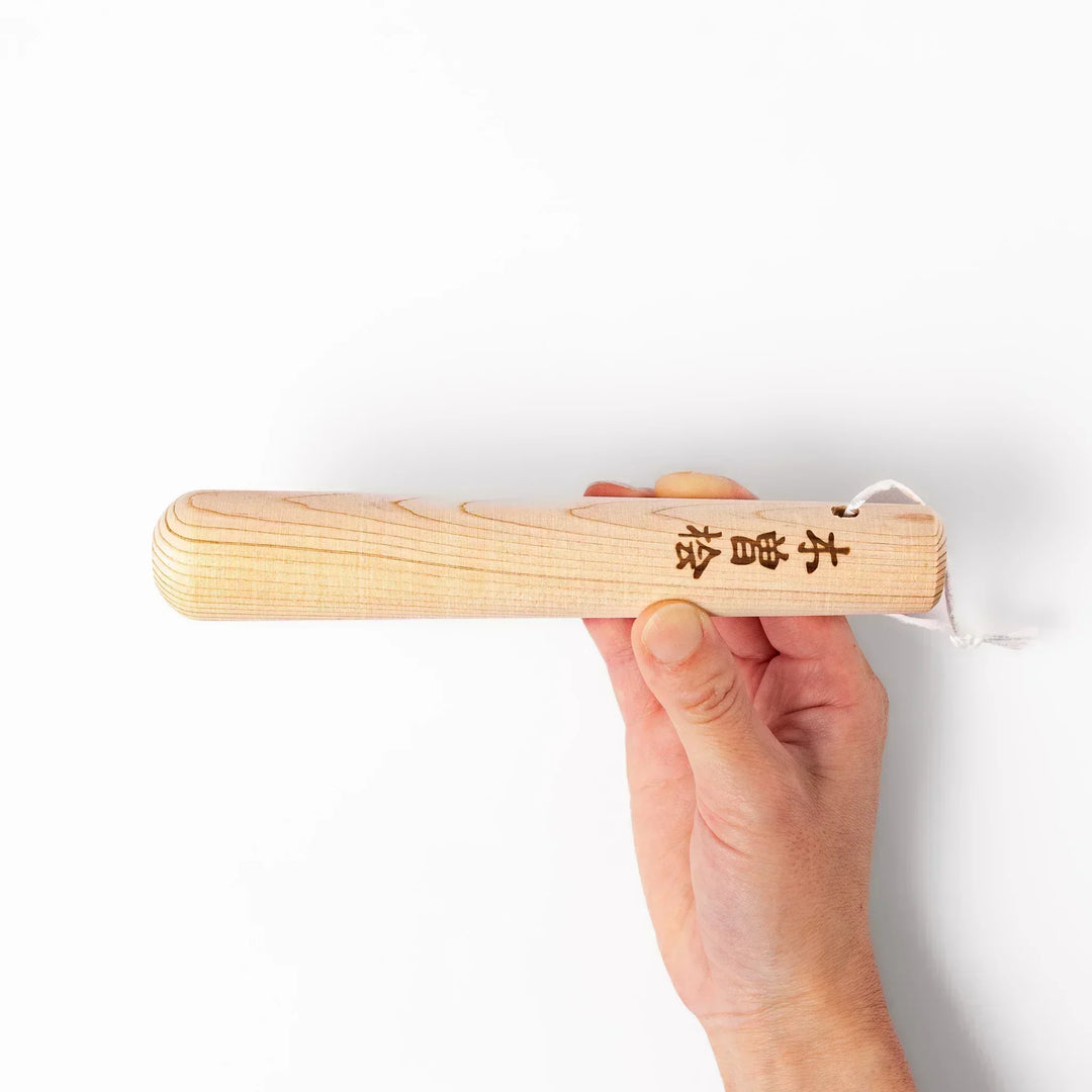 Hinoki wood pestle with engraved Japanese characters and hanging cord, crafted for use with suribachi mortars to grind seeds and spices smoothly.