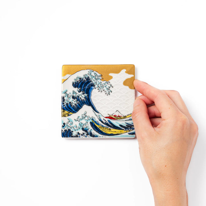 Square Japanese ceramic coaster featuring Hokusai’s Great Wave design with dramatic blue waves, golden sky, and Mt. Fuji, bringing iconic art to dining tables.