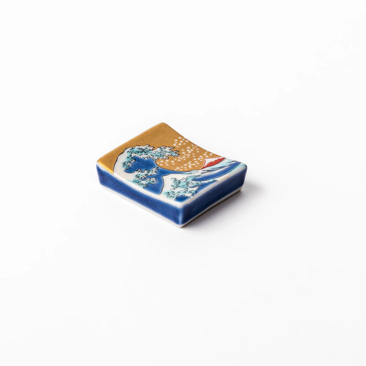 Rectangular Japanese ceramic chopstick rest featuring Hokusai’s Great Wave design with vivid blue wave, golden sky, and Mt. Fuji, adding iconic artistry to dining.