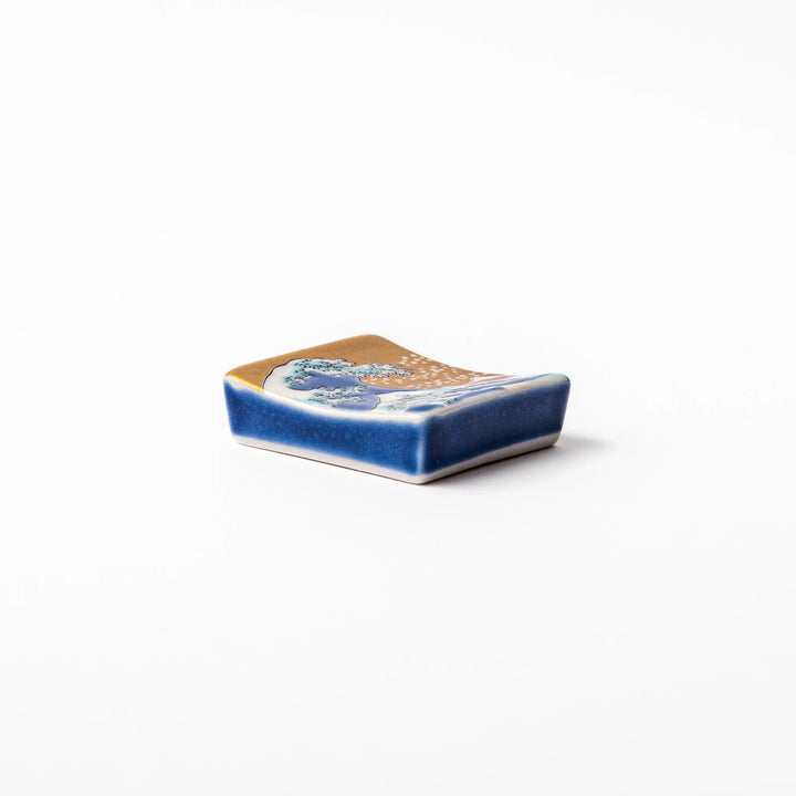 Rectangular Japanese ceramic chopstick rest featuring Hokusai’s Great Wave design with vivid blue wave, golden sky, and Mt. Fuji, adding iconic artistry to dining.