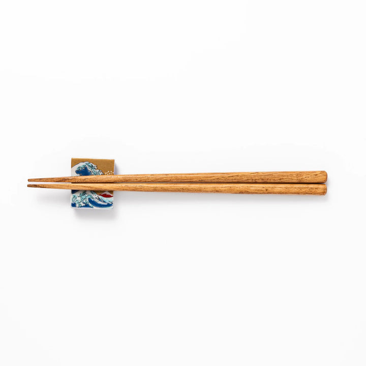 Rectangular Japanese ceramic chopstick rest featuring Hokusai’s Great Wave design with vivid blue wave, golden sky, and Mt. Fuji, adding iconic artistry to dining.