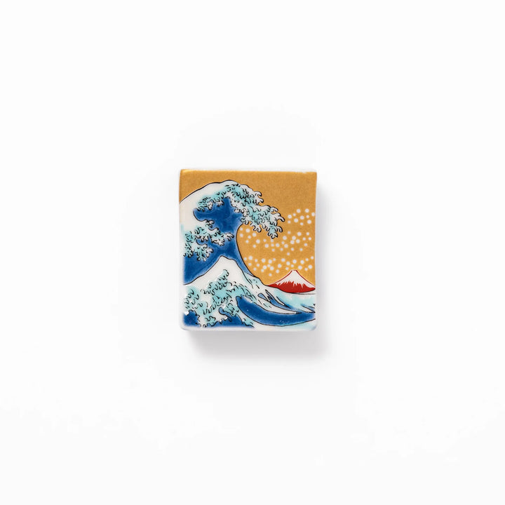 Rectangular Japanese ceramic chopstick rest featuring Hokusai’s Great Wave design with vivid blue wave, golden sky, and Mt. Fuji, adding iconic artistry to dining.