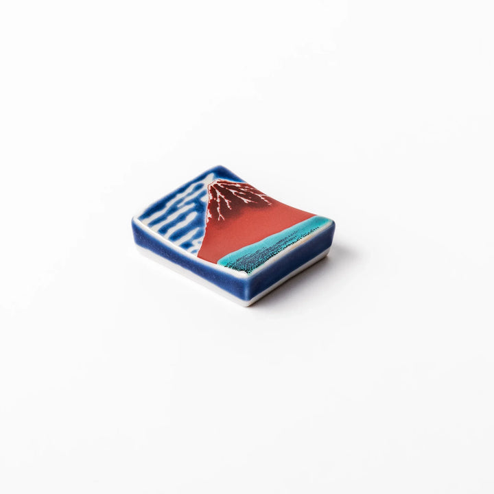 Rectangular Japanese ceramic chopstick rest featuring Hokusai’s Red Fuji design with vivid red mountain and blue sky, bringing iconic artistry to dining tables.