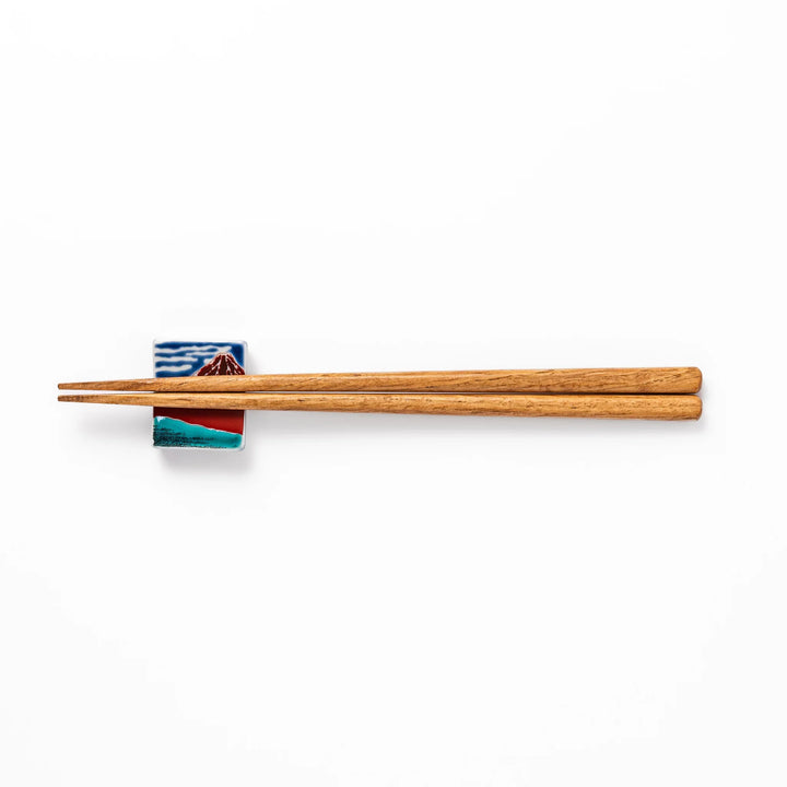 Rectangular Japanese ceramic chopstick rest featuring Hokusai’s Red Fuji design with vivid red mountain and blue sky, bringing iconic artistry to dining tables.