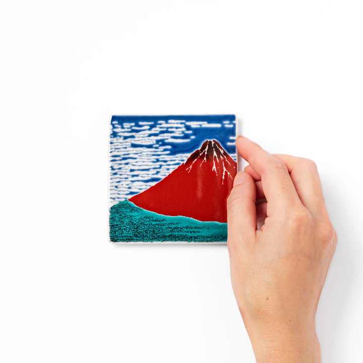 Square Japanese ceramic coaster featuring Hokusai’s Red Fuji design with vivid red mountain, blue sky, and clouds, adding iconic artistry to dining tables.