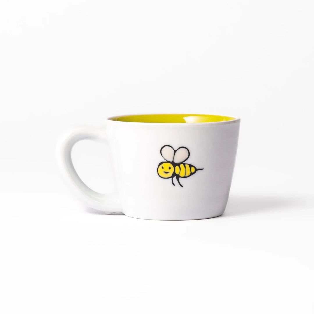 White ceramic kids mug featuring friendly honey bear face, yellow interior, round handle, shown on white background