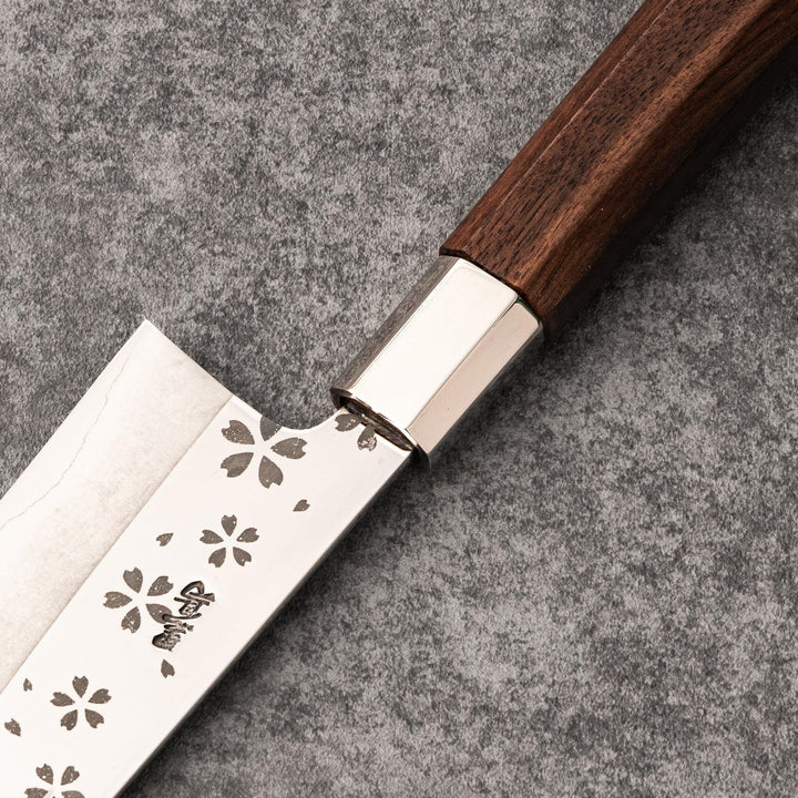Elegant Japanese kitchen knife with cherry blossom cutout pattern on the blade, featuring a sharp edge and dark wooden handle for precise cutting.