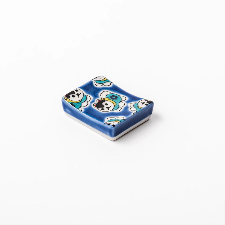 Rectangular Japanese ceramic chopstick rest with a deep blue background decorated with playful lucky dog motifs, bringing charm and fun to dining tables.