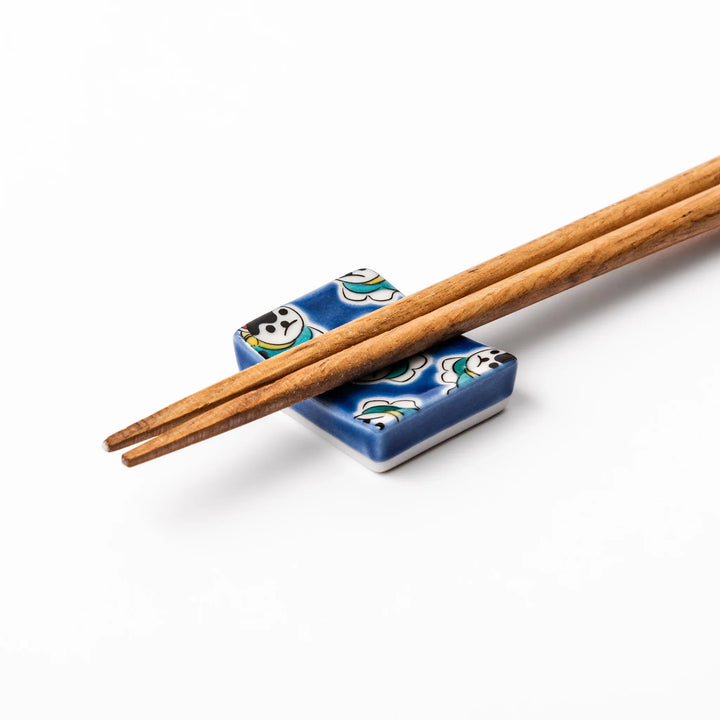 Rectangular Japanese ceramic chopstick rest with a deep blue background decorated with playful lucky dog motifs, bringing charm and fun to dining tables.