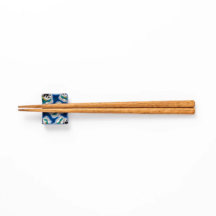 Rectangular Japanese ceramic chopstick rest with a deep blue background decorated with playful lucky dog motifs, bringing charm and fun to dining tables.
